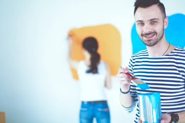 Yeni evin içini boyayan mutlu, genç bir çiftin portresi. Genç çift