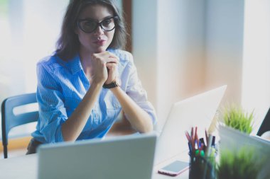 Ofis masasında dizüstü bilgisayarla oturan genç bir kadın. Genç bir kadın. Dizüstü bilgisayar