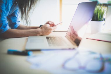 Ofis masasında oturan ve cep telefonuyla konuşan genç ve güzel bir iş kadını. İş kadını