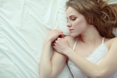 Güzel bir kadın yatağında uzanıyor..