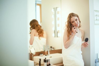 Telefon ile banyo üzerinde duran genç kadın.