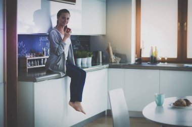 modern mutfakta otururken cep telefonu kullanan kadın.