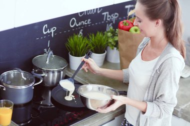 Genç bayan masanın yanında dururken mutfakta krep hazırlıyor. Mutfaktaki kadın. Mutfakta yemek yapmak..