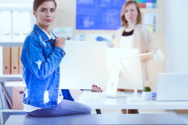 Masanın yanında duran iki genç kadın enstrüman, plan ve dizüstü bilgisayarla.