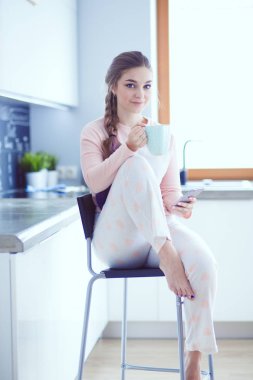 modern mutfakta otururken cep telefonu kullanan kadın.