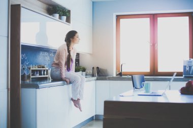 Mutfakta masada oturan genç kadın.