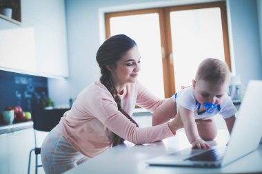 Annesi bebeğini evde parlak mutfakta ile.