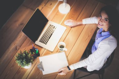 Masasında oturan ve elinde bir fincan kahveyle rahatlamış genç bir kadının portresi. İş kadını. İşyeri