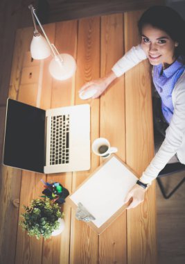 Masasında oturan ve elinde bir fincan kahveyle rahatlamış genç bir kadının portresi. İş kadını. İşyeri