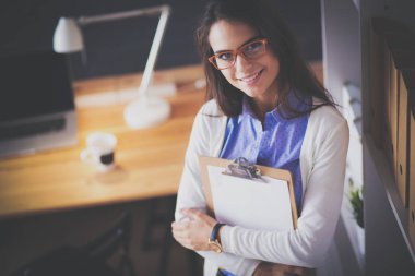 Masanın yanında dizüstü bilgisayarı ve bir fincan kahveyle duran genç bir kadın. İş yeri. İş Kadını.