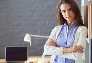 Dizüstü bilgisayarının yanında duran genç bir kadın.