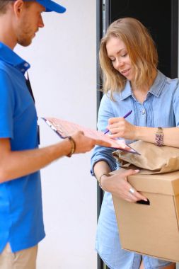 Mavi üniformalı gülümseyen kurye servis konseptine paket kutusu teslim eden teslimatçı. Mavi üniformalı gülümseyen teslimatçı.