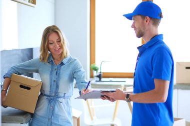 Mavi üniformalı gülümseyen kurye servis konseptine paket kutusu teslim eden teslimatçı. Mavi üniformalı gülümseyen teslimatçı.