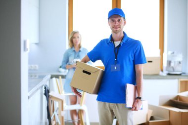 Mavi üniformalı gülümseyen kurye servis konseptine paket kutusu teslim eden teslimatçı. Mavi üniformalı gülümseyen teslimatçı.