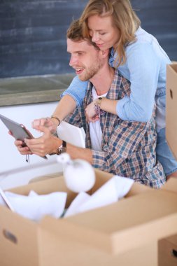 Genç bir çift yeni ev içinde hareket. Oturma ve açma sonra rahatlatıcı. Bir şey üstünde laptop arıyorum. Genç Çift