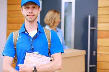 Mavi üniformalı gülümseyen kurye servis konseptine paket kutusu teslim eden teslimatçı. Mavi üniformalı gülümseyen teslimatçı.