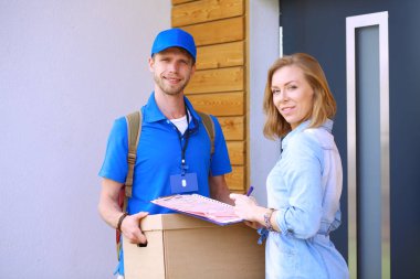 Mavi üniformalı gülümseyen kurye servis konseptine paket kutusu teslim eden teslimatçı. Mavi üniformalı gülümseyen teslimatçı.