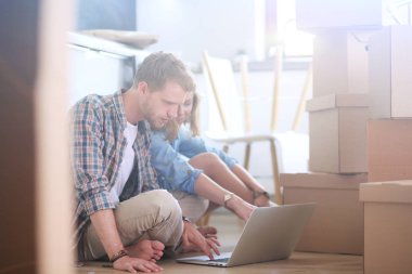 Genç bir çift yeni ev içinde hareket. Oturma ve açma sonra rahatlatıcı. Bir şey üstünde laptop arıyorum. Genç Çift