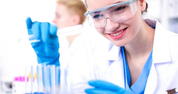 Woman researcher is surrounded by medical vials and flasks, isolated on white background — Stock Photo, Image