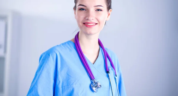 Médico sonriente con una carpeta en uniforme de pie en el hospital —  Fotos de Stock