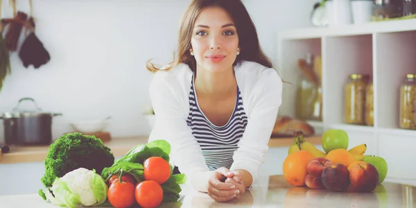 Mujer joven sentada cerca de escritorio en la cocina — Foto de Stock