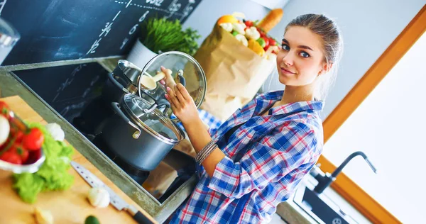 Jonge vrouw bij het fornuis in de keuken — Stockfoto