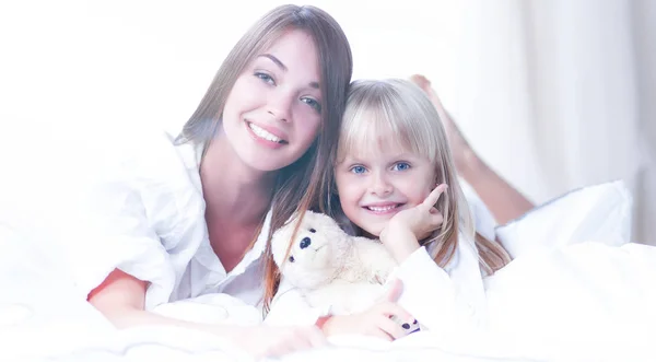 Woman and young girl lying in bed smiling — Stock Photo, Image