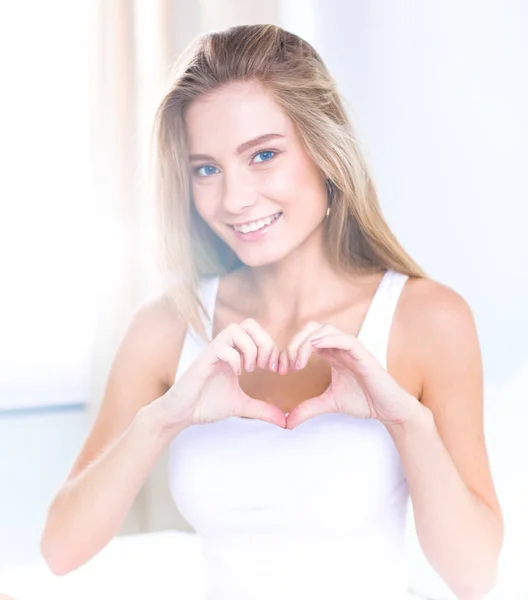 Beautiful woman showing heart shape on her hand , sitting bed — Stock Photo, Image