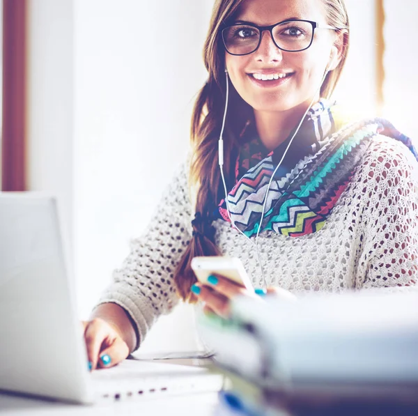 Kitapların arasında masa başında oturan genç bir kadın.