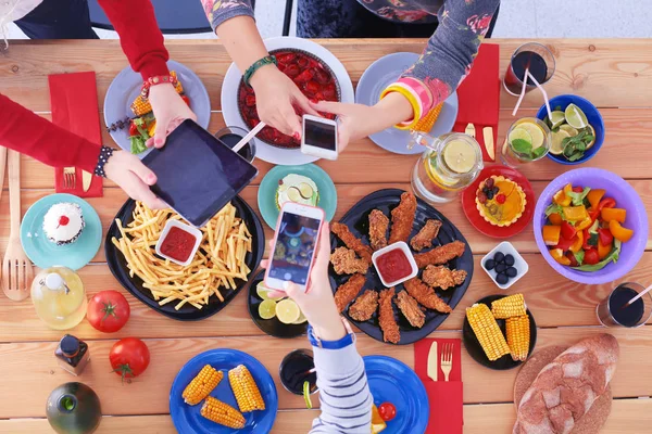 Κάτοψη της ομάδας των ανθρώπων που έχουν δείπνο μαζί, ενώ κάθεται στο ξύλινο τραπέζι. Φαγητό στο τραπέζι. Οι άνθρωποι τρώνε φαστ φουντ. Φωτογραφία τροφίμων — Φωτογραφία Αρχείου