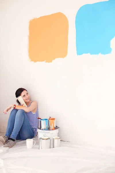 Женщина выбирает цвет краски из образцов для нового дома, сидя на деревянном полу. Женщина в доме — стоковое фото