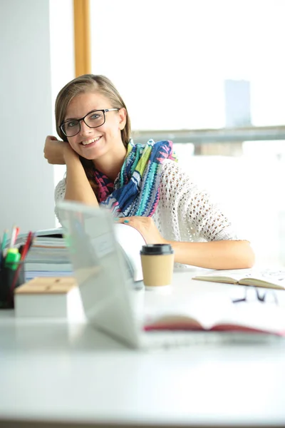 Jonge vrouw zit achter een bureau tussen de boeken. Studenten — Stockfoto