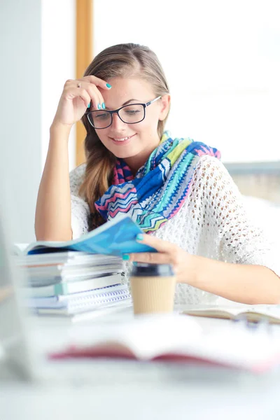 Mladá žena sedící za stolem mezi knihami. Student — Stock fotografie