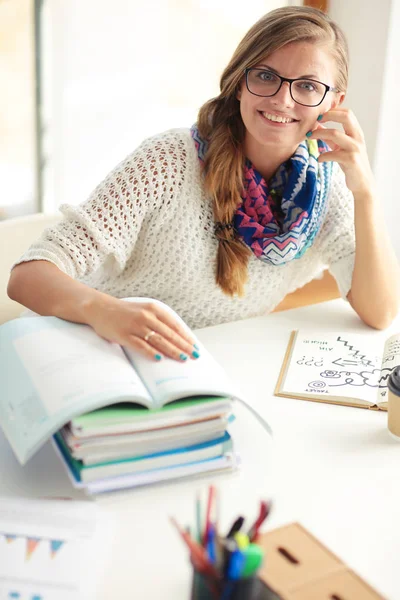 Jeune femme assise à un bureau parmi les livres. Étudiant — Photo