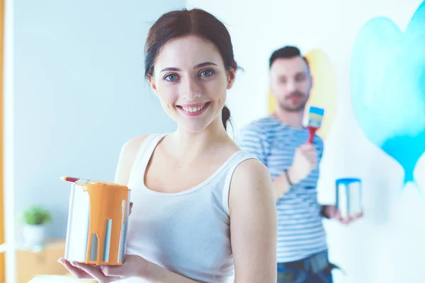 Portrait de jeune couple souriant heureux peignant mur intérieur de la maison neuve. jeune couple — Photo