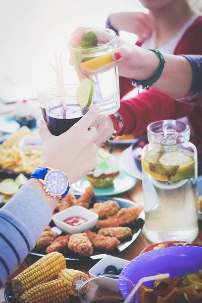 Ahşap masada otururken birlikte yemek yiyen bir grup insanın üst düzey görüntüsü. Masada yemek var. İnsanlar fast food yiyor..