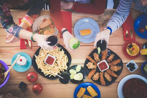 Vista dall'alto del gruppo di persone che cenano insieme seduti a un tavolo di legno. Cibo sul tavolo. La gente mangia fast food. — Foto Stock