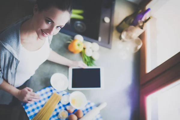 Hermosa mujer cocinando pastel en la cocina de pie cerca del escritorio. — Foto de Stock