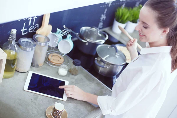 Mujer joven parada junto a la estufa en la cocina. Mujer cocinando en la cocina . — Foto de Stock