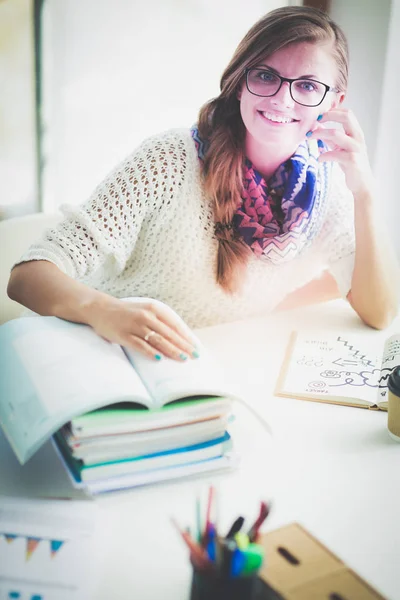 Jonge vrouw zit achter een bureau tussen de boeken. Studenten — Stockfoto