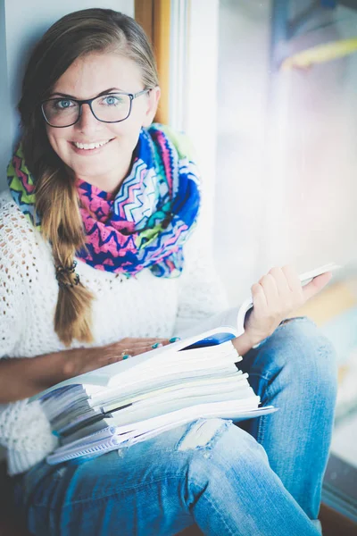 Jonge vrouw zit achter een bureau tussen de boeken. Studenten — Stockfoto