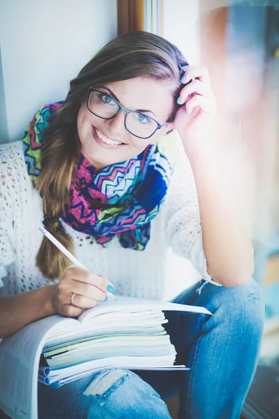 Jonge vrouw zit achter een bureau tussen de boeken. Studenten — Stockfoto