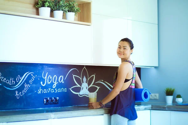 Retrato de una mujer sonriente sosteniendo en su mano una esterilla de yoga mientras estaba de pie en el estudio. Yoga. Una mujer. Bienestar — Foto de Stock