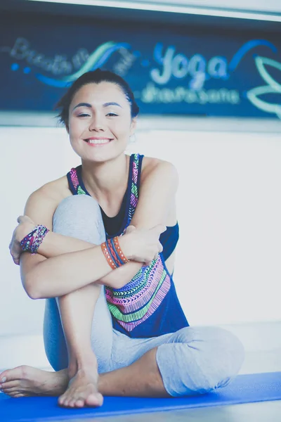 Retrato de una mujer sonriente de yoga sentada en la esterilla de yoga después del entrenamiento en el estudio de yoga. Yoga. Mujer. . — Foto de Stock