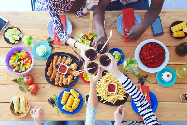 Vista superior do grupo de pessoas que jantam juntas enquanto estão sentadas à mesa de madeira. Comida na mesa. As pessoas comem fast food. — Fotografia de Stock