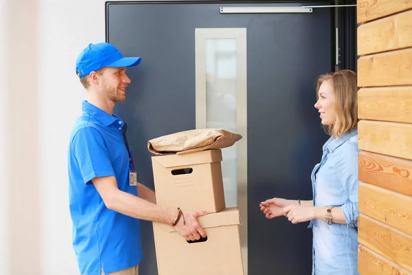 Leende leverans man i blå uniform leverera paket låda till mottagaren - kurir service koncept. Leende leverans man i blå uniform — Stockfoto