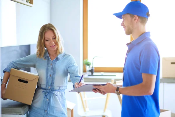 Repartidor sonriente con uniforme azul que entrega la caja de paquetes al destinatario: concepto de servicio de mensajería. Repartidor sonriente en uniforme azul — Foto de Stock