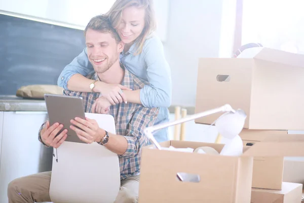 Jong koppel bewegen in nieuwe huis. Zitten en te ontspannen na het uitpakken. Zoek iets op laptop. Jong koppel — Stockfoto