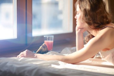 Pencere yakınındaki erken sabah yatakta yatan kadın.