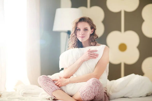 젊은 여자는 동안 그녀의 침대에 앉아 베개를 들고. — 스톡 사진
